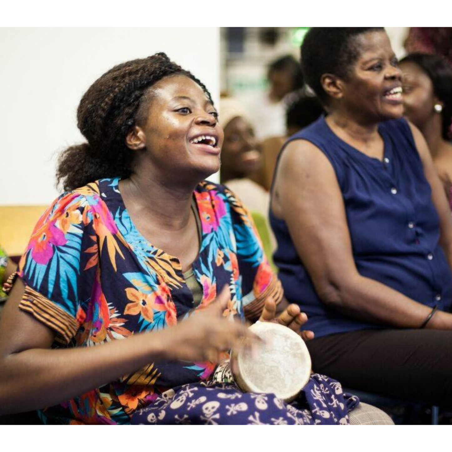 Two women sitting down and singing.