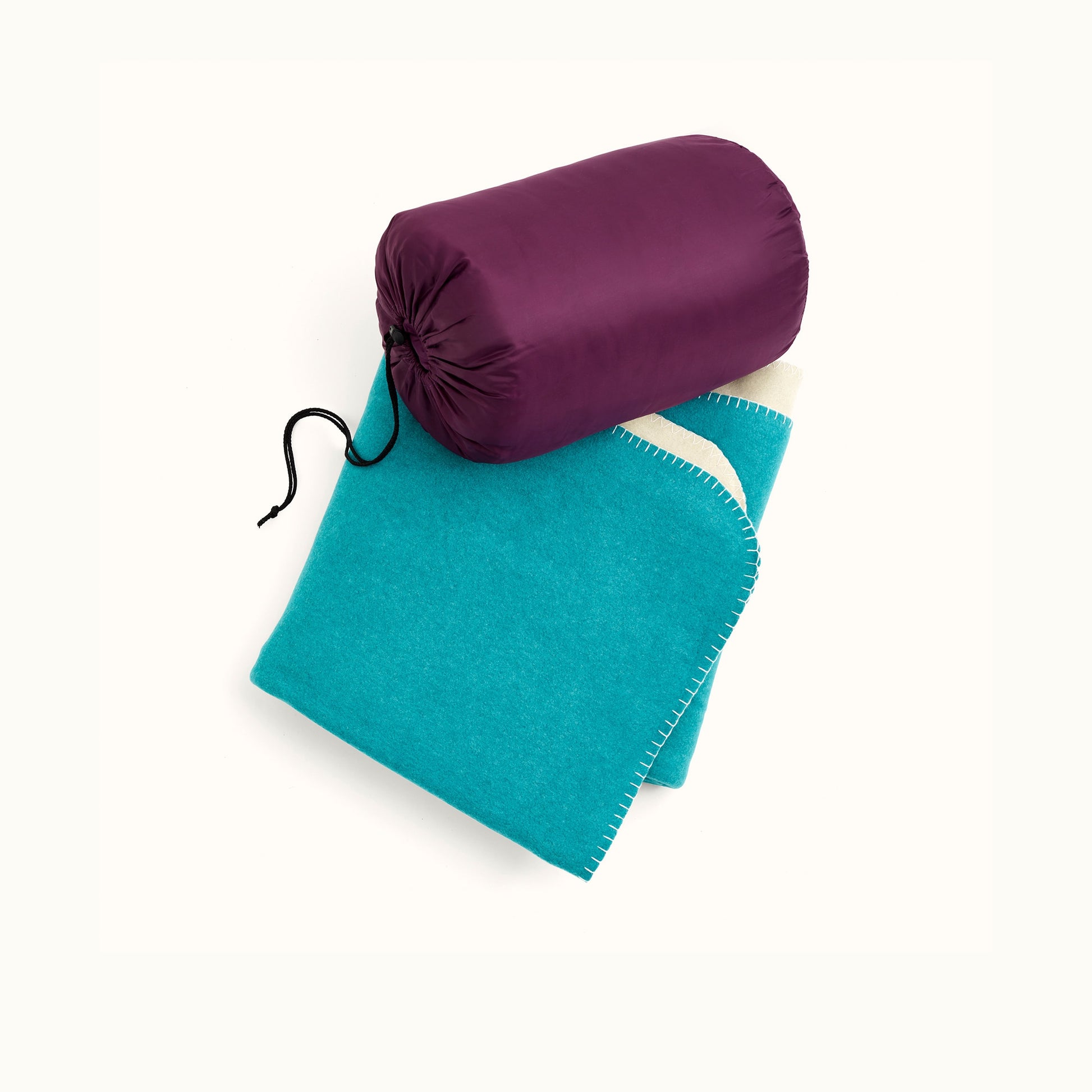 In the image there is a thick light blue blanket folder and placed in the middle on the phtoo, with a thermal sleeping bag in a burgundy sack placed on the top line of the blanket.