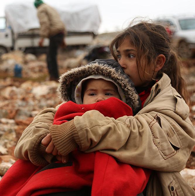 Child holds baby with a warm blanket